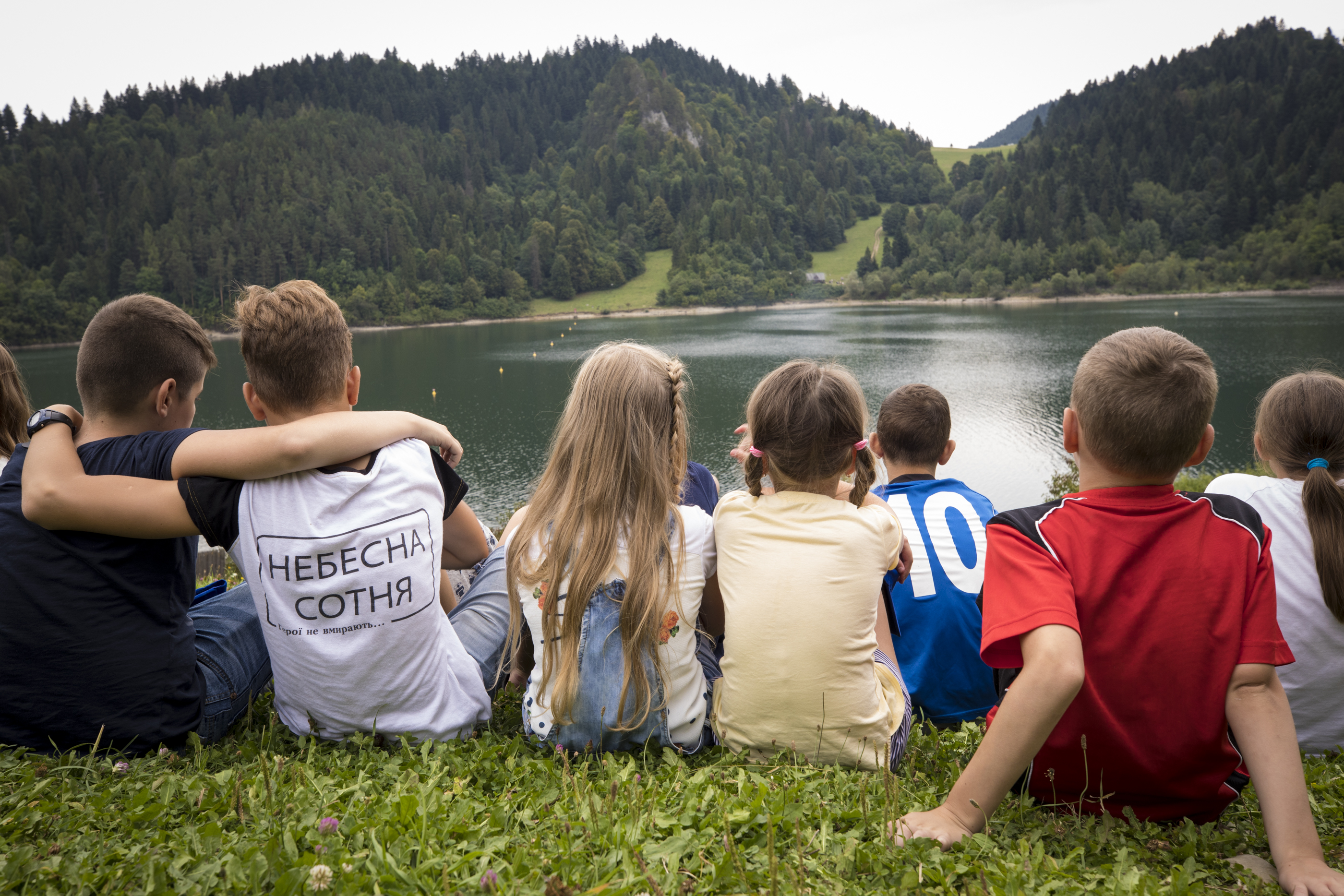Children sit by a lake in Poland. All the children have lost parents or had parents severely injured in the conflict in Ukraine. Children sit by a lake in Poland. All the children have lost parents or had parents severely injured in the conflict in Ukraine.